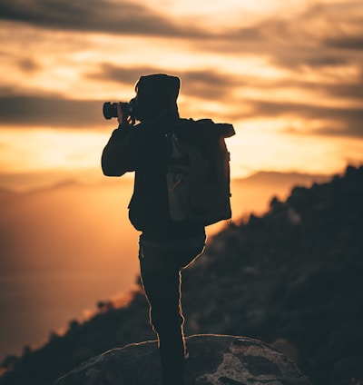 silhouette of man holding camera during sunset