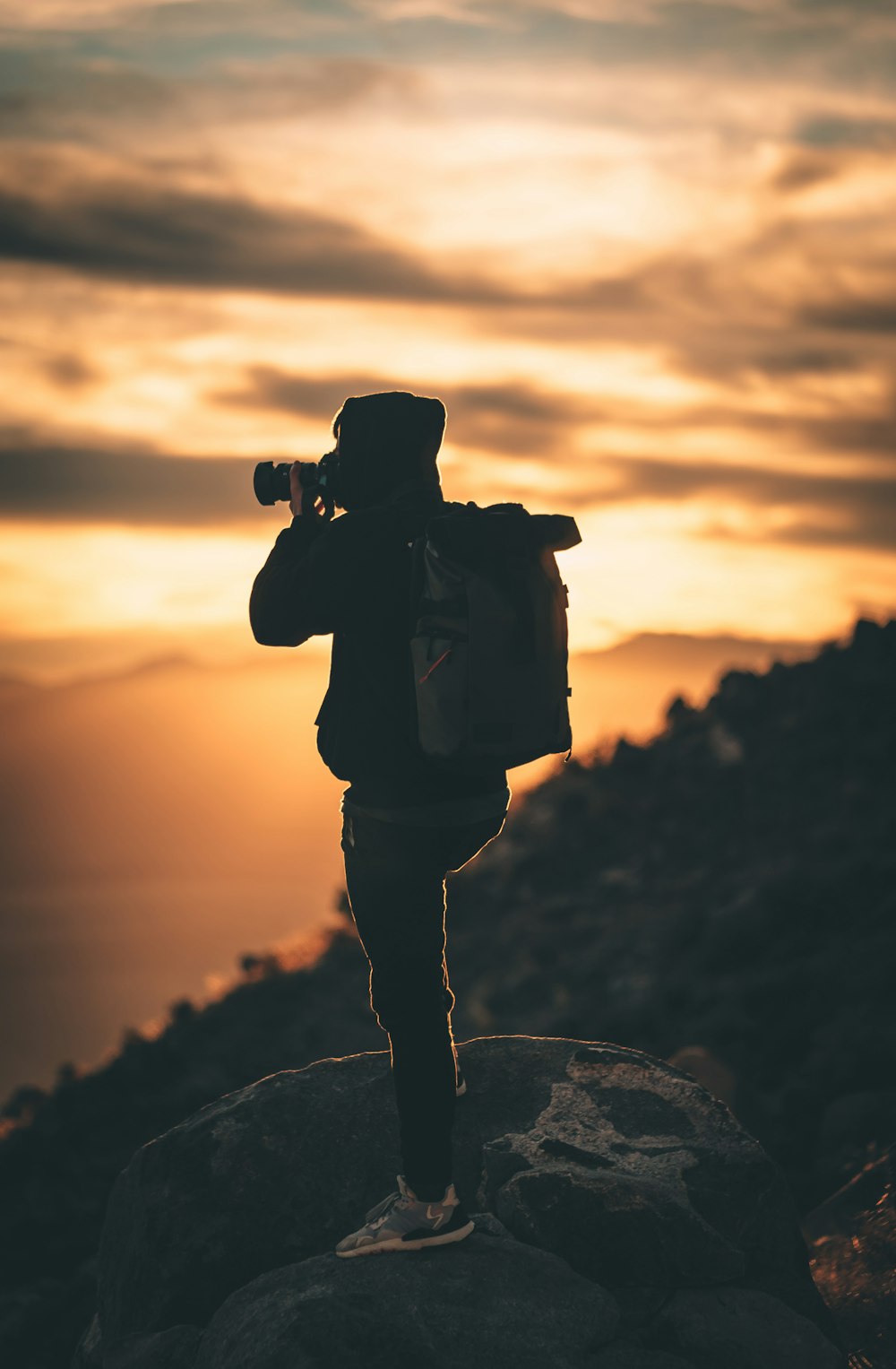 silhouette of man holding camera during sunset