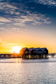 silhouette of houses near body of water during sunset