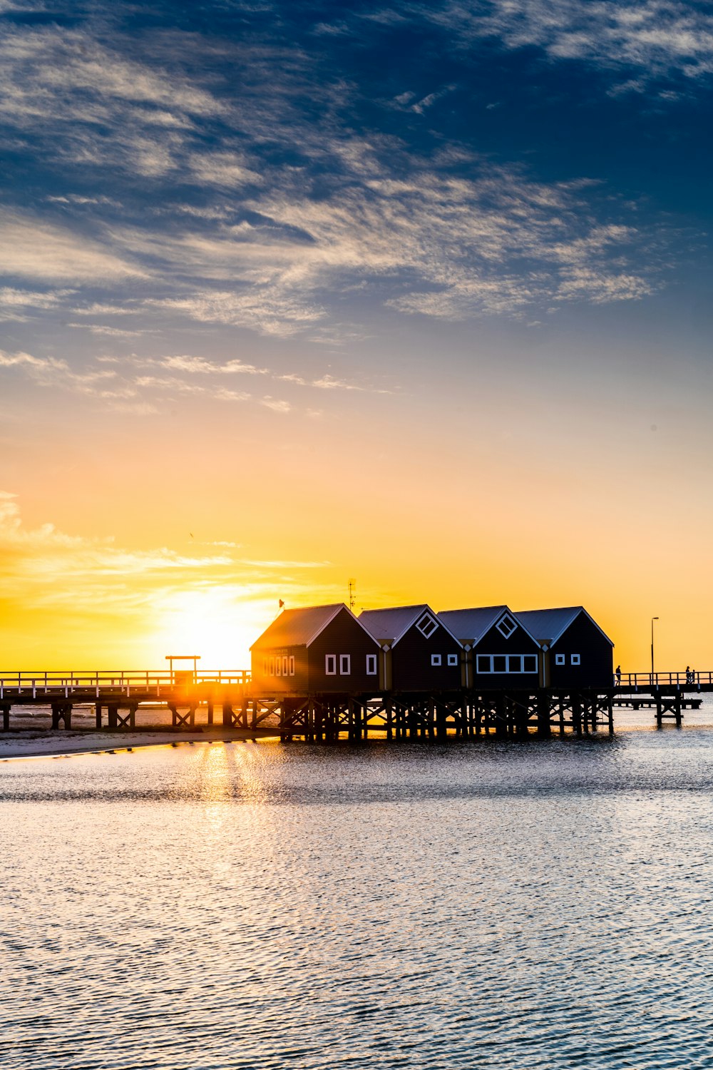 silhouette of houses near body of water during sunset