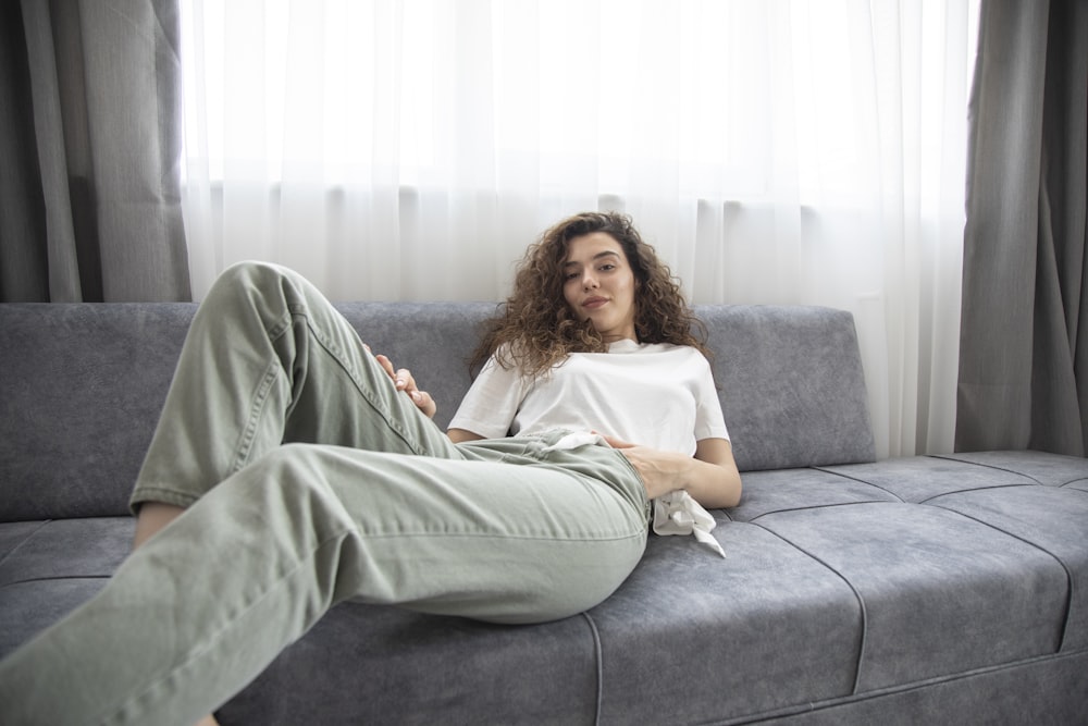 woman in green shirt lying on gray couch
