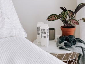 Close-up of bedside table with a water pitcher, tissues, and a small lamp.