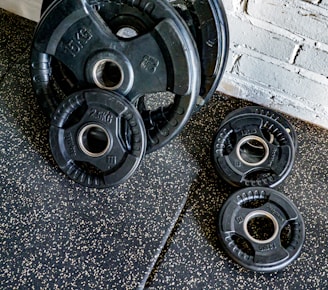 A collection of rusty gym weights and dumbbells on a wooden floor.