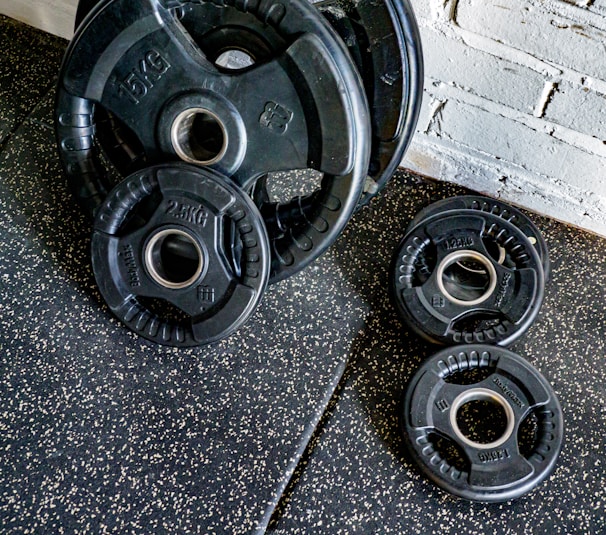 A collection of rusty gym weights and dumbbells on a wooden floor.