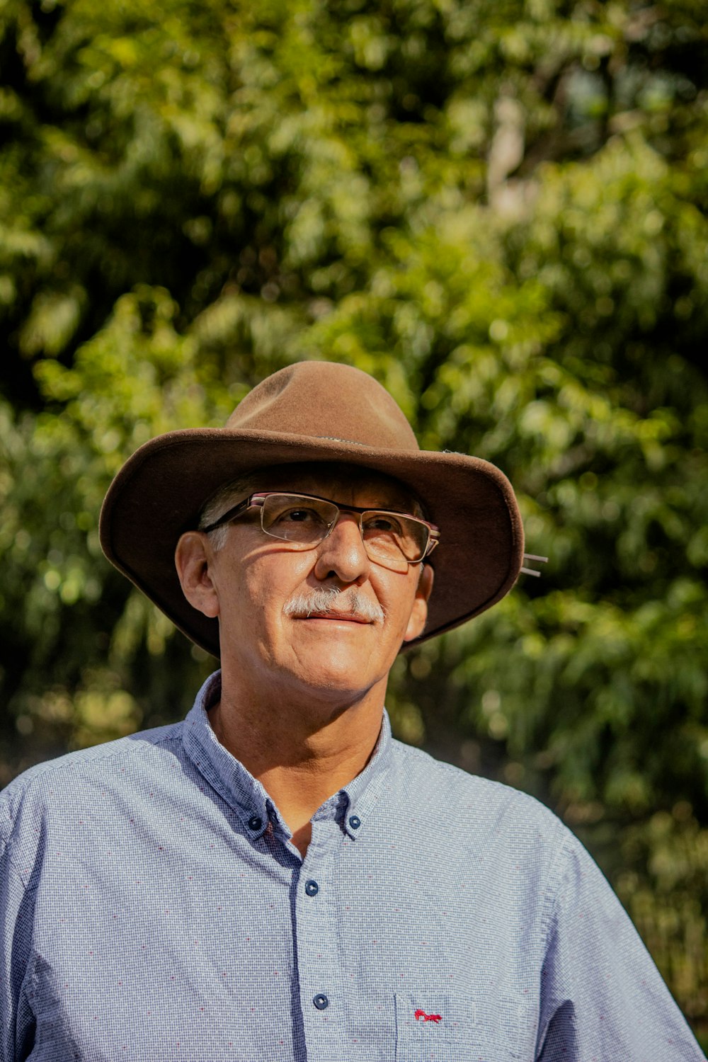 Hombre con camisa gris abotonada con sombrero fedora marrón