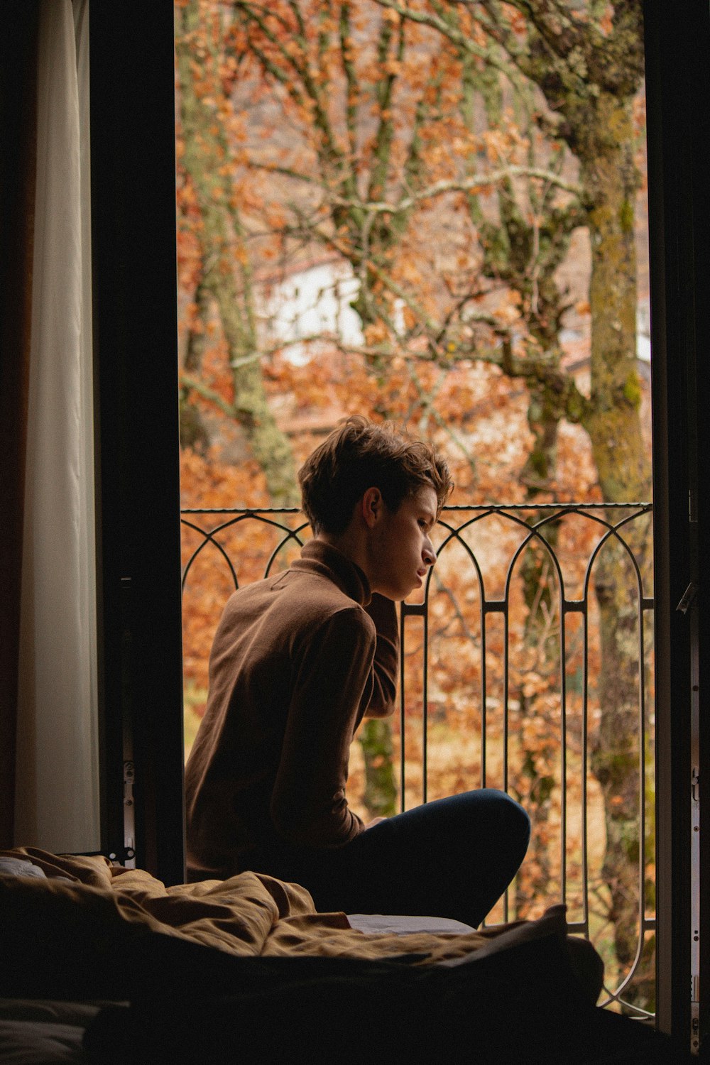 woman in brown long sleeve shirt sitting on window