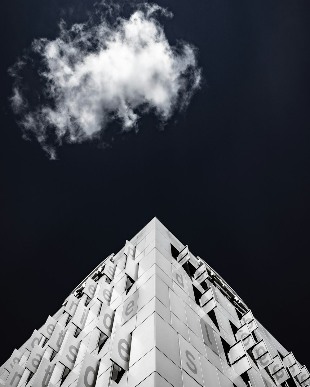흐린 하늘 아래 콘크리트 건물의 그레이스케일 사진