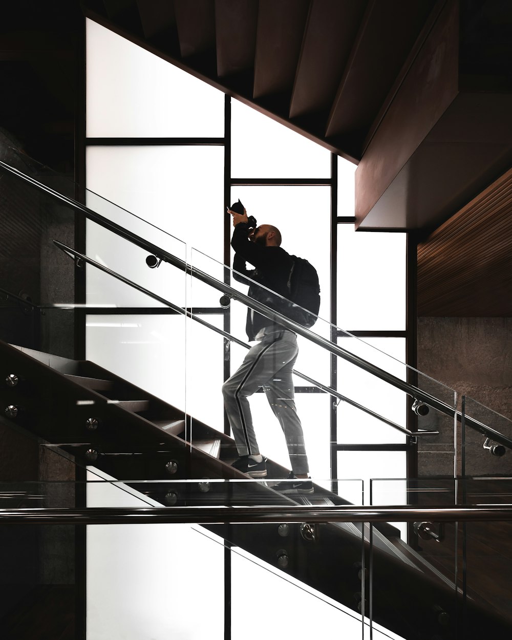 man in black t-shirt and blue denim jeans standing on black wooden staircase