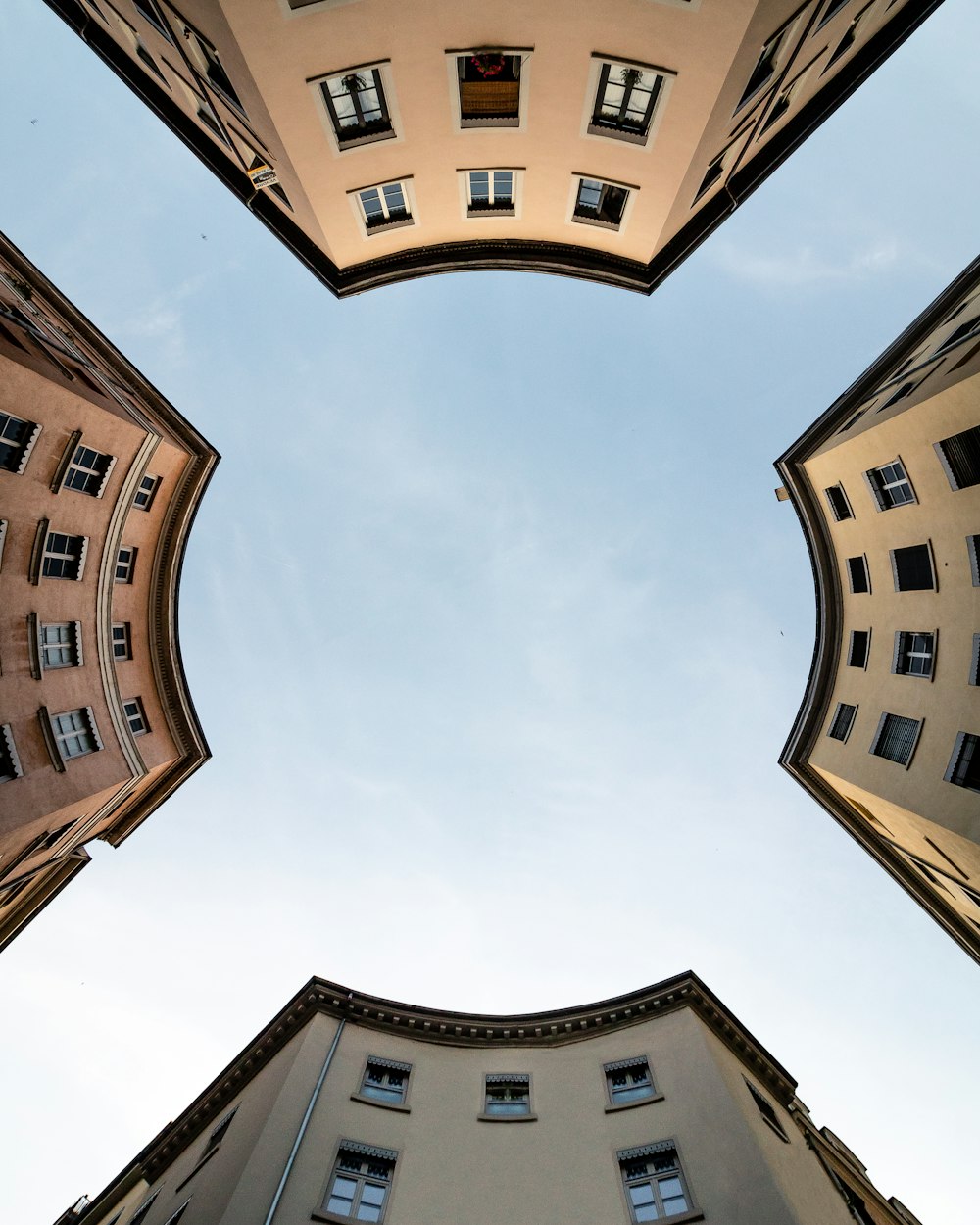 fotografia ad angolo basso dell'edificio in cemento marrone sotto nuvole bianche durante il giorno