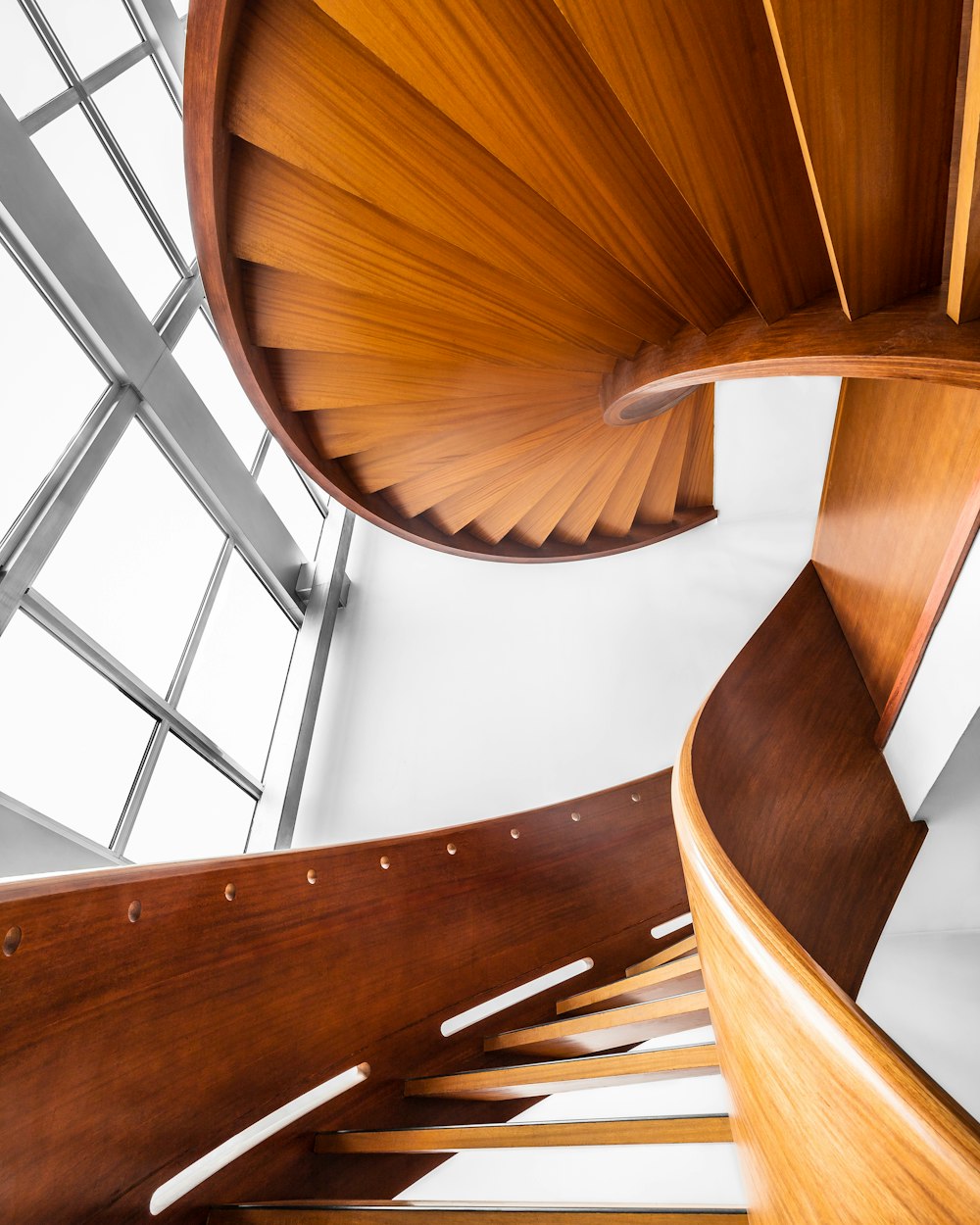 Escalera de caracol de madera marrón sobre pared pintada de blanco