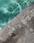 A swimming pool edge with clear aqua-colored water on one side and a concrete surface on the other. The concrete shows markings of '4 FT' indicating the water depth. The surface has areas of wear and discoloration.