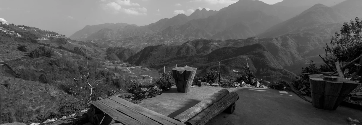 a black and white photo of a bench and mountains