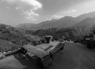 a black and white photo of a bench and mountains