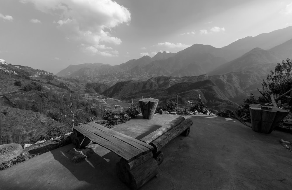 a black and white photo of a bench and mountains