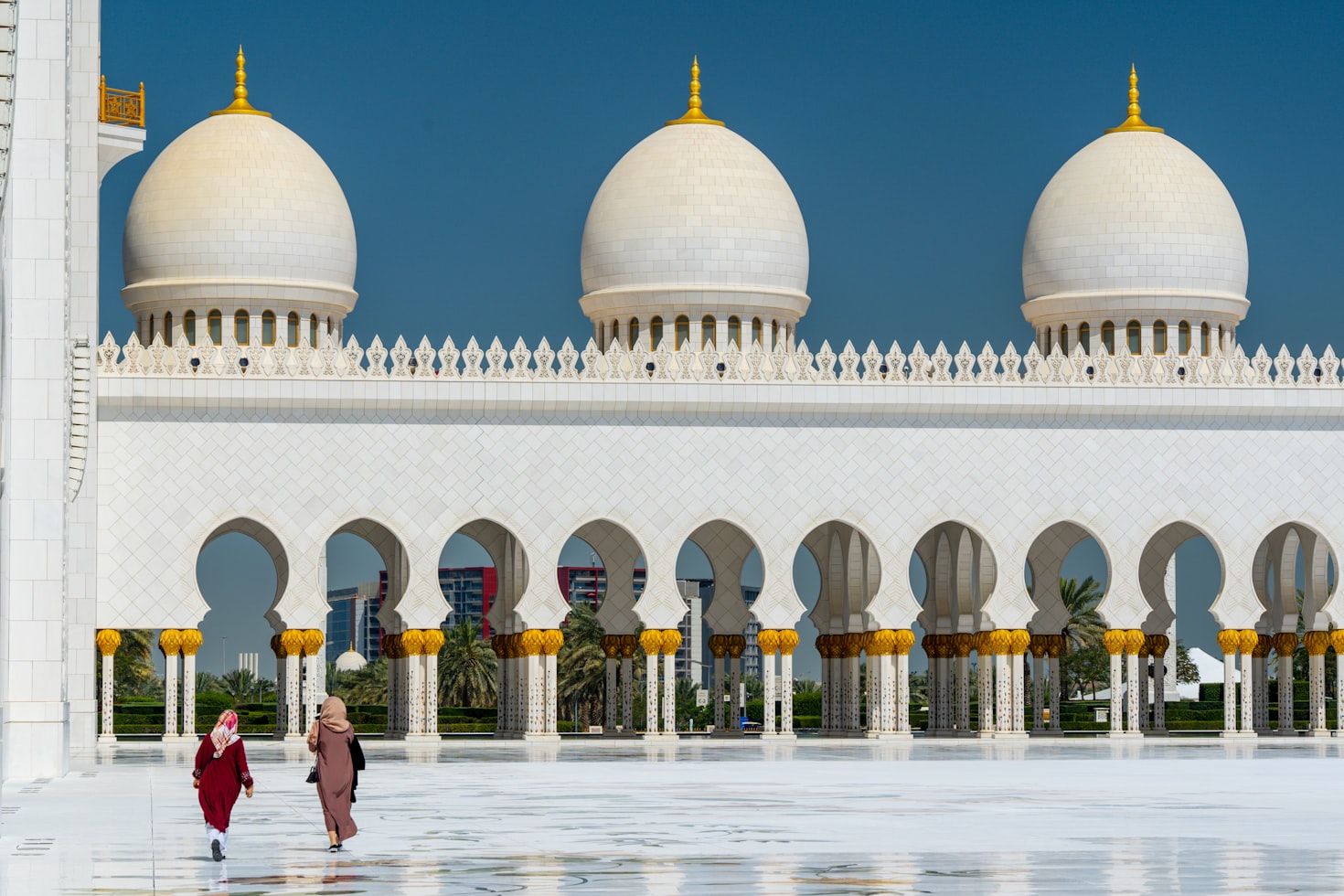 People walking across courtyard of one of the largest mosque in Sheik Zayed Grand Mosque, Abu Dhabi, UAE