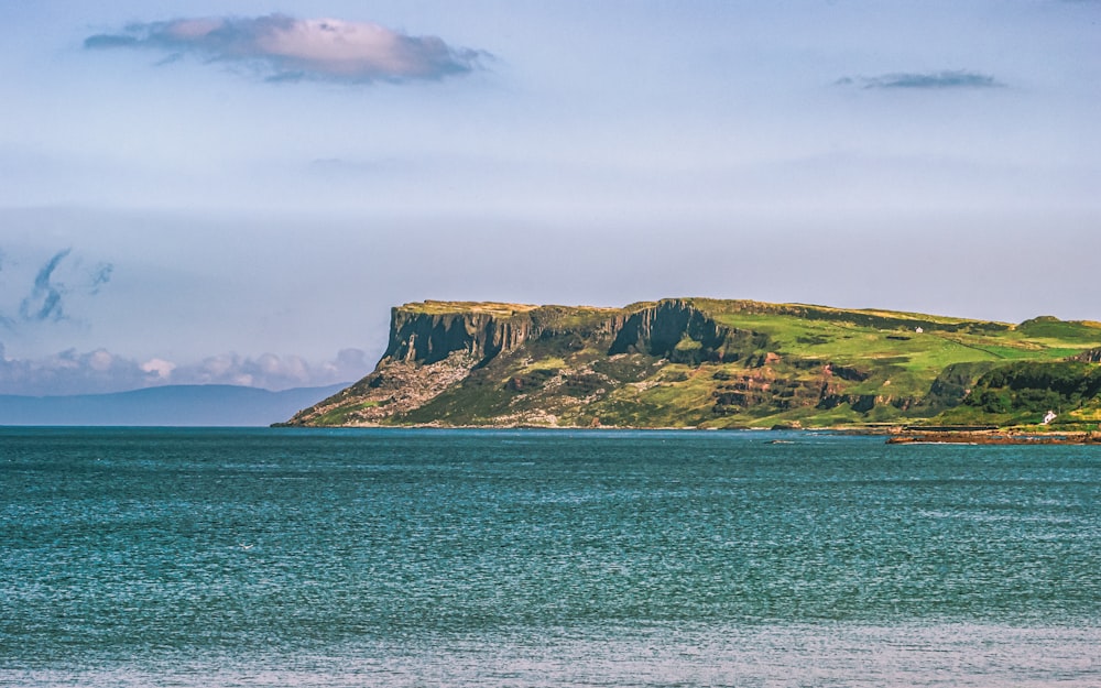 brown and green mountain beside body of water during daytime