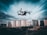 A drone is flying in the foreground above a grassy or dirt area, with a backdrop of tall residential apartment buildings under a cloudy sky. The image captures a dynamic perspective with the drone in focus as it hovers, showcasing the details of the urban landscape.