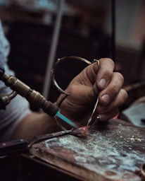Personne dans un atelier en train de faire fondre un matériau avec une lampe à souder