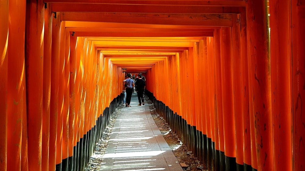 man in black jacket and black pants walking on orange tunnel