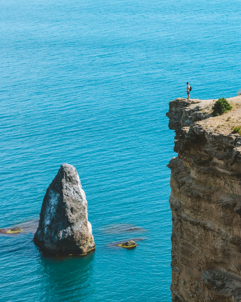 person standing on rock formation near body of water during daytime