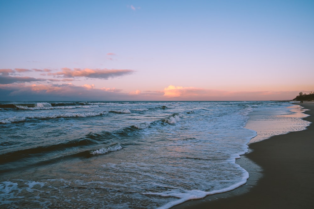 Olas del océano rompiendo en la costa durante la puesta de sol