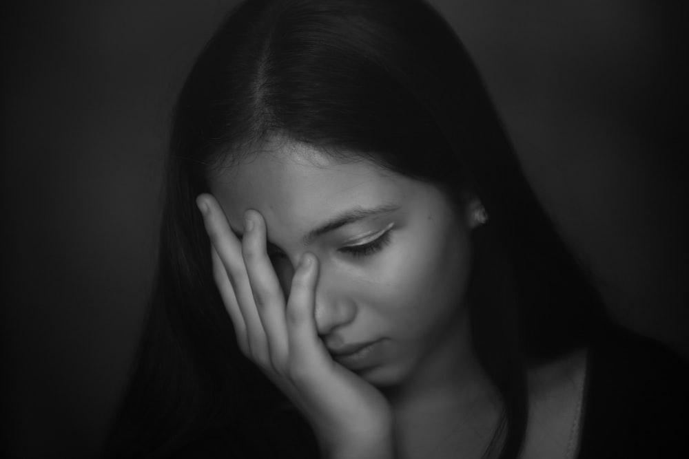 grayscale photo of woman with hand on her face