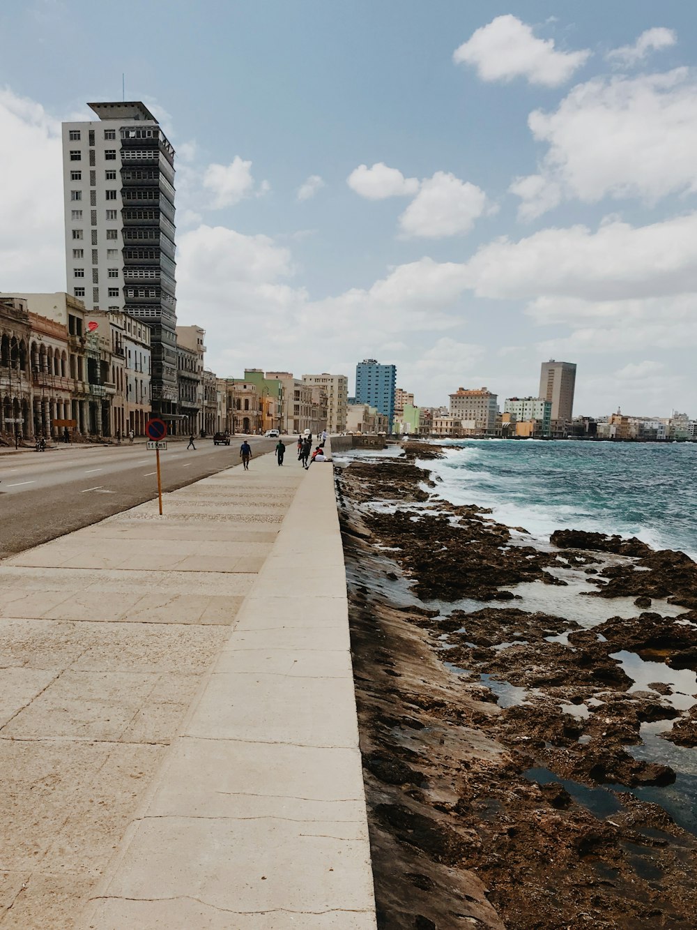 people walking on concrete pathway near sea during daytime