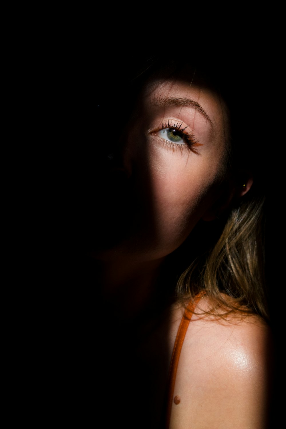 woman with green eyes wearing orange tank top