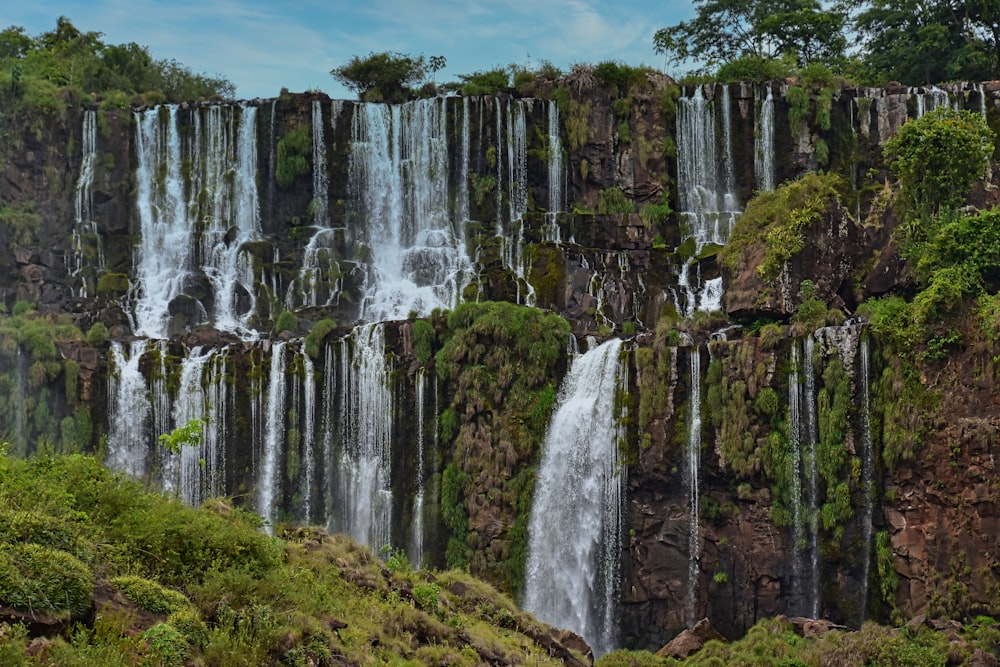 waterfalls on green grass field during daytime