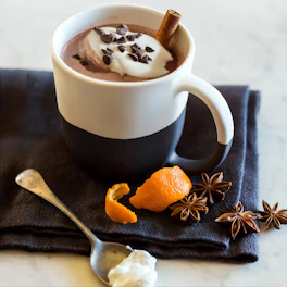 A vibrant bowl of magnesium cocoa powder mixed into a creamy hot chocolate with a cinnamon stick.