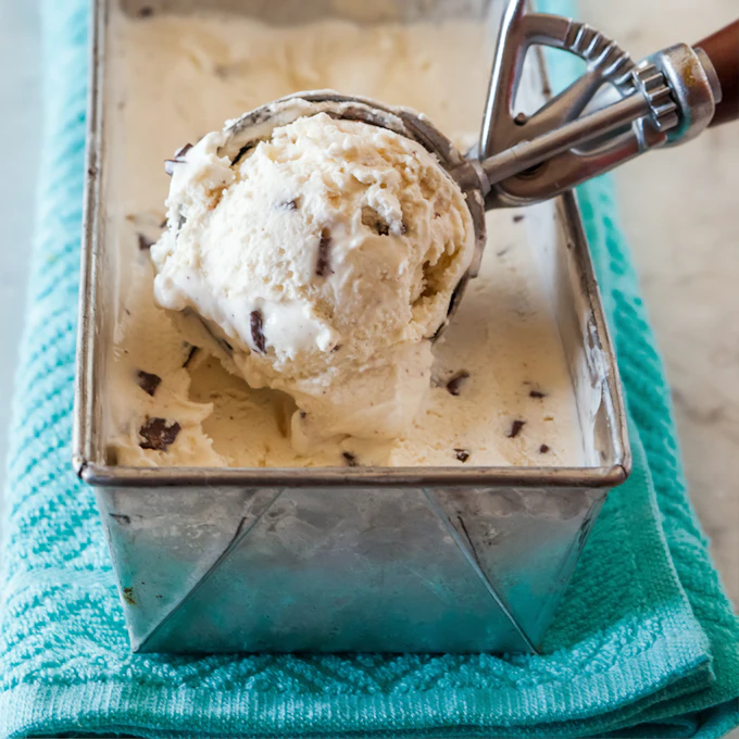 A scoop of fresh ice cream being lifted from the tub in the display case