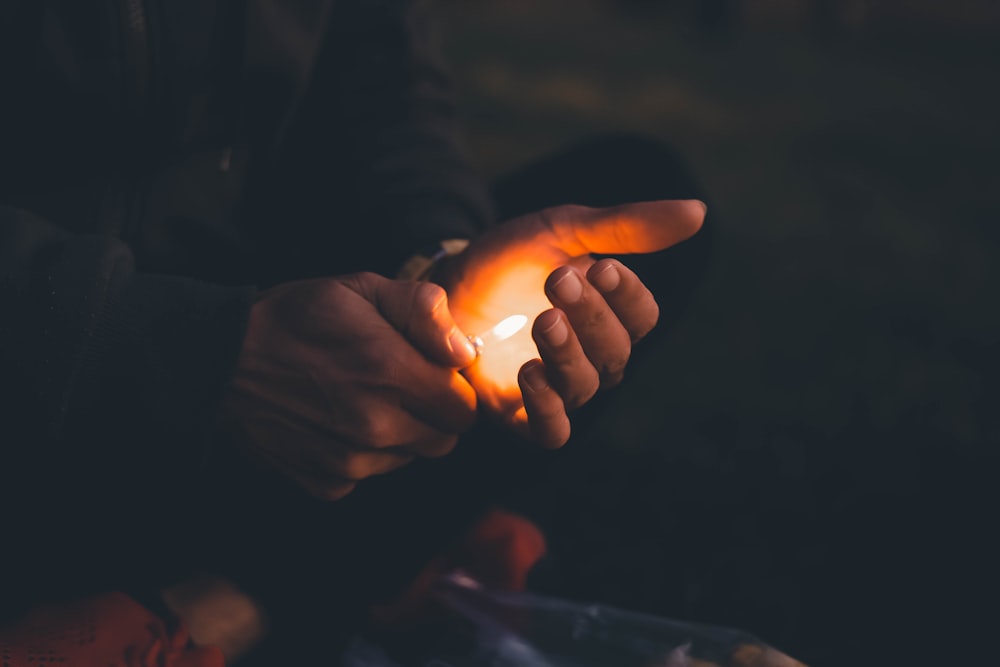 person holding lighted candle during nighttime