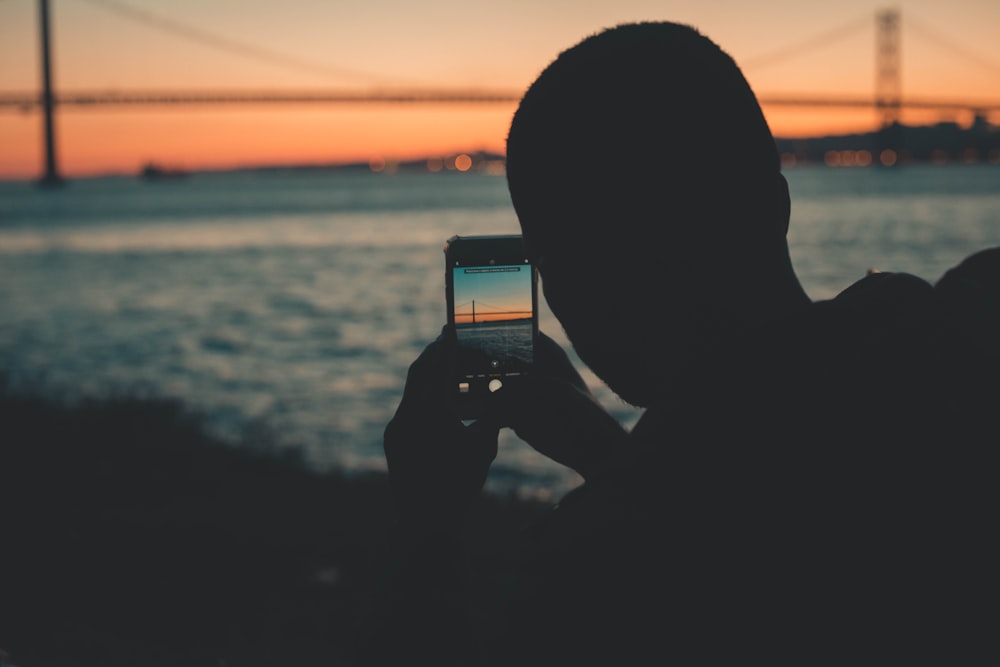 Silhouette eines Mannes, der den Sonnenuntergang fotografiert