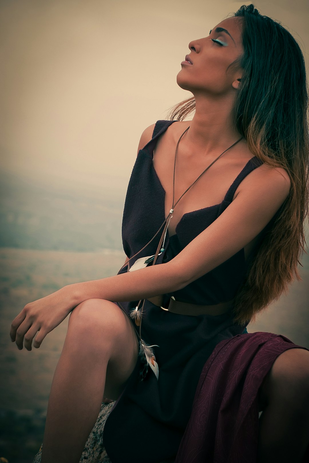 woman in black tank top and red skirt sitting on brown rock