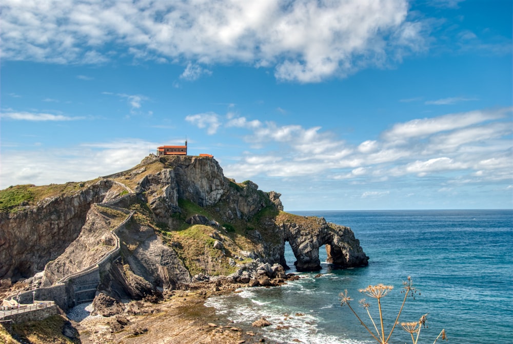 formação rochosa marrom e verde no mar sob o céu azul durante o dia