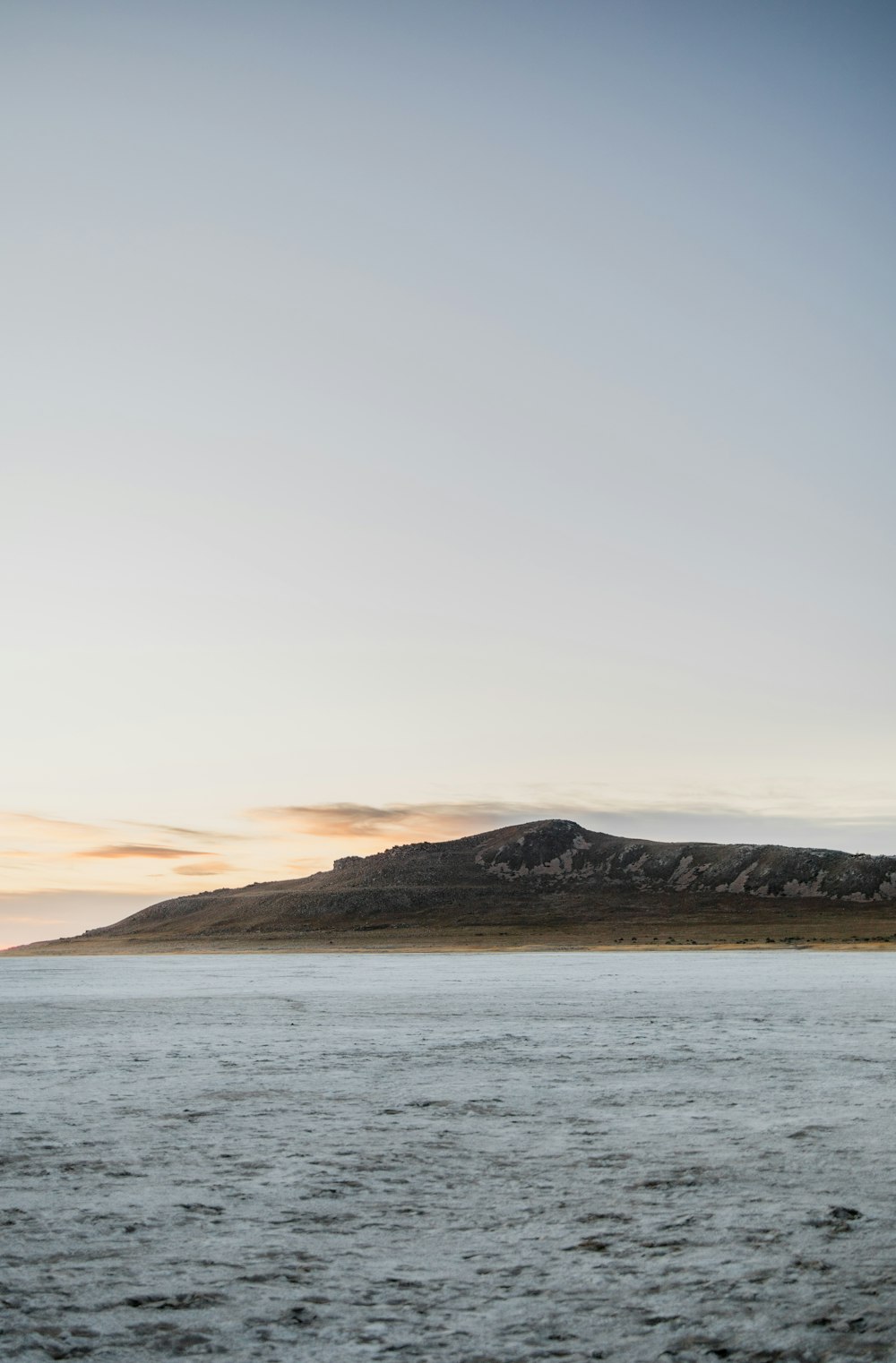 brown mountain near body of water during daytime