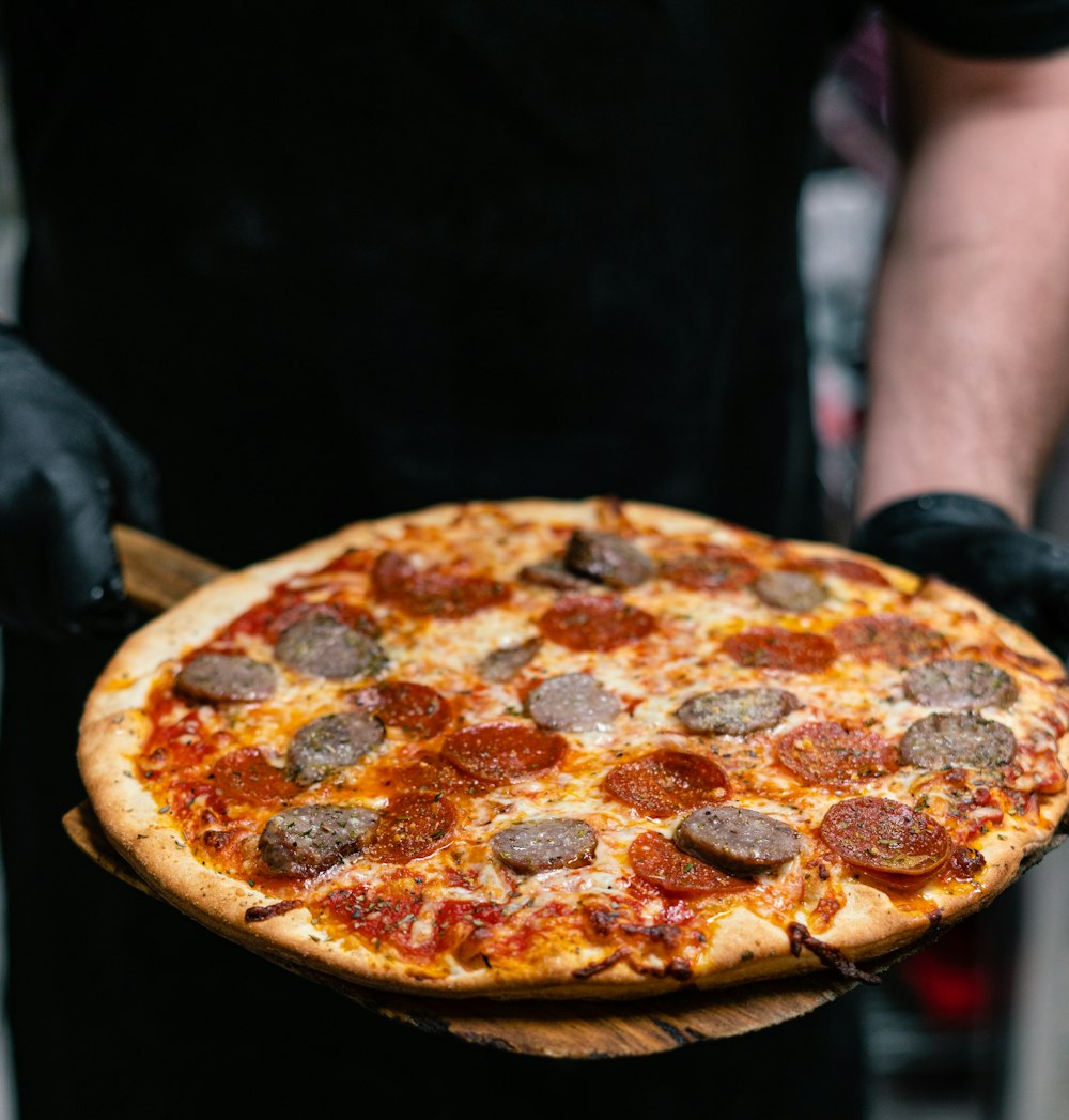 person holding pizza with cheese