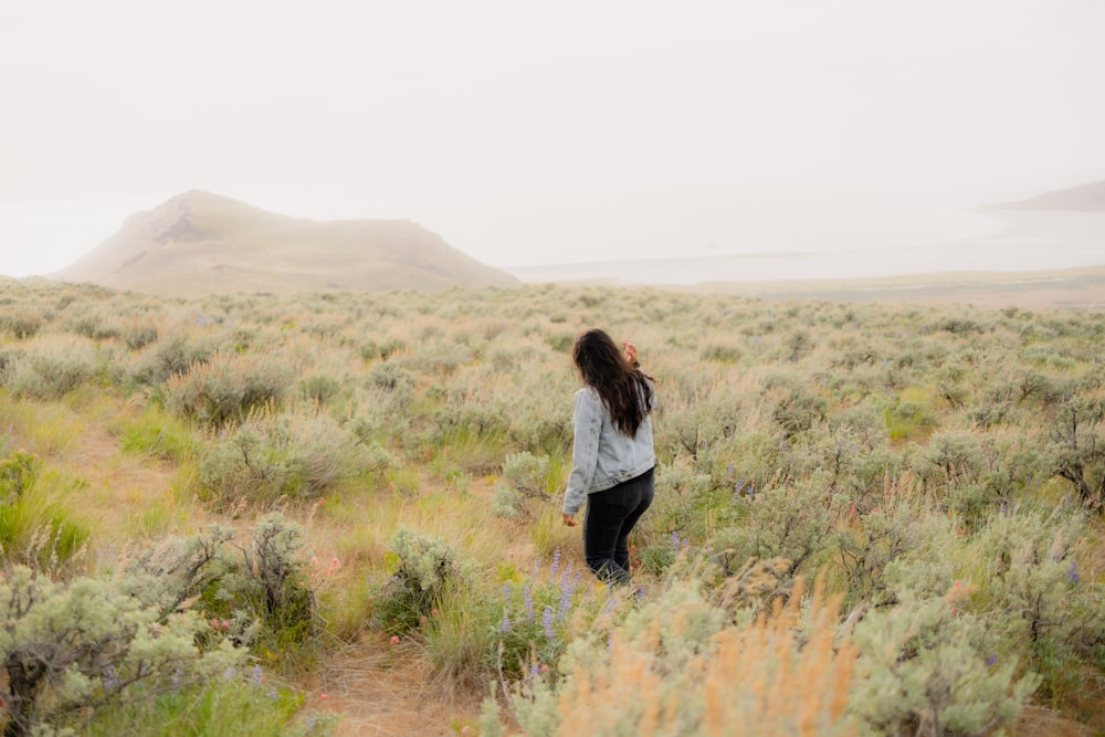 woman in white long sleeve shirt and black pants standing on brown grass field during daytime