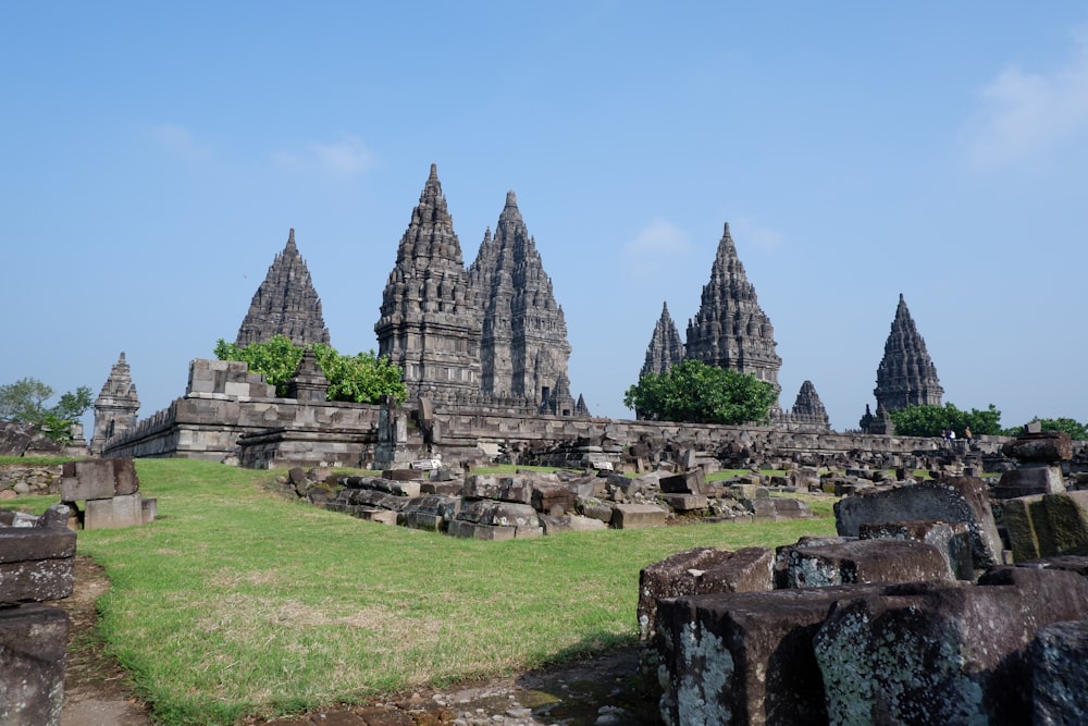 gray concrete ruins on green grass field under blue sky during daytime