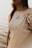 A person is partially visible, wearing a tie-dye T-shirt with the text 'this is a positive message.' They are carrying a beige tote bag, and the background features a soft, blurred view of what appears to be water, suggesting a peaceful outdoor setting.
