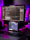 Developer coding on multiple monitors with dark-themed tech workspace.