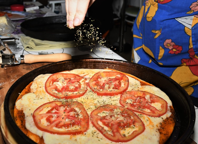 A close-up of a homemade pizza topped with fresh vegetables and herbs.