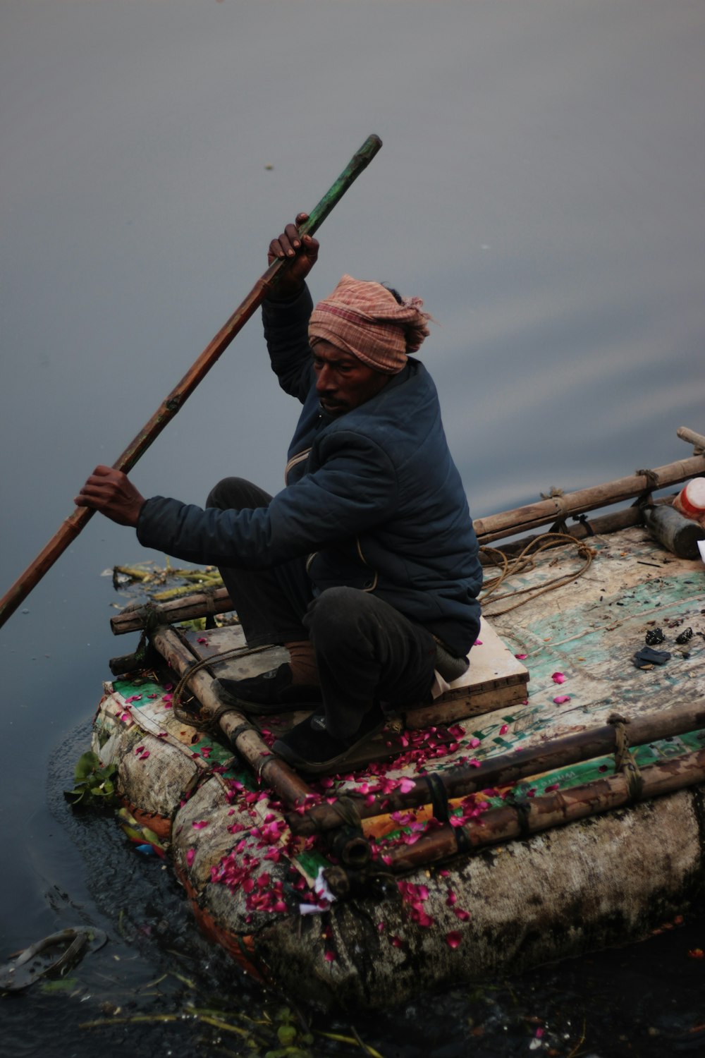 man in blue denim jeans and red knit cap sitting on brown wooden boat during daytime