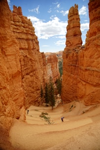 person walking on white sand near brown rock formation during daytime
