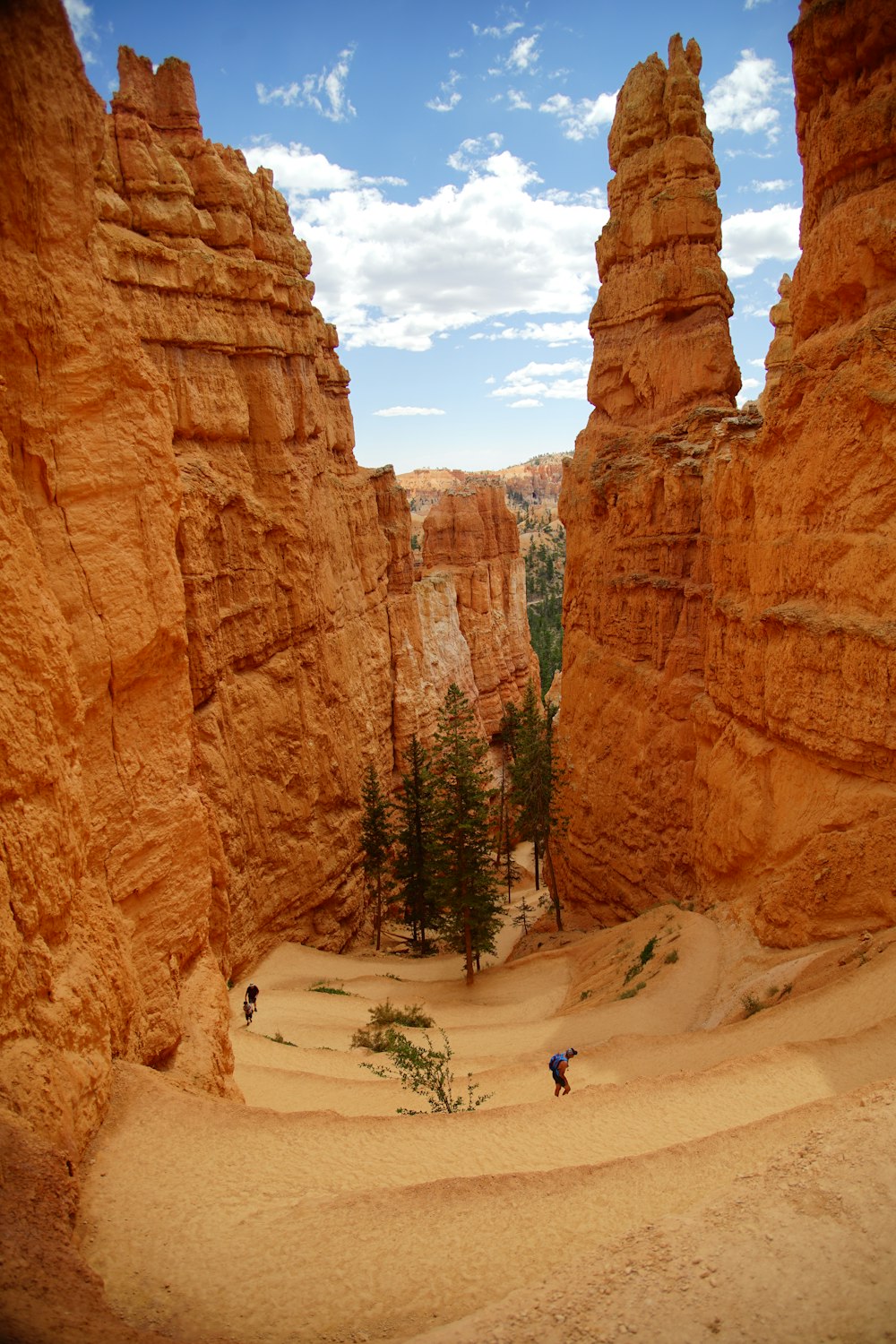 person walking on white sand near brown rock formation during daytime