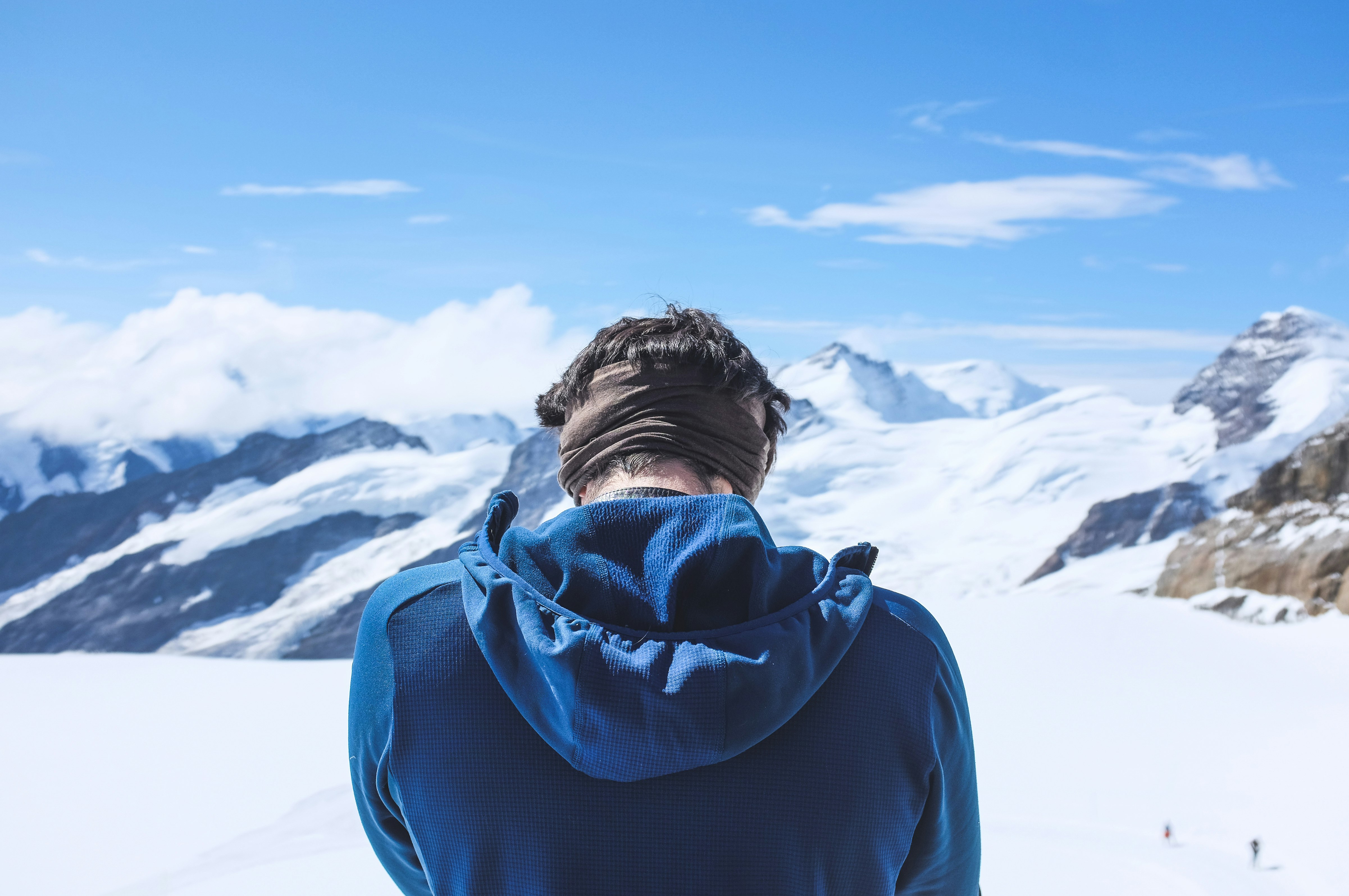 man in blue hoodie standing on snow covered ground during daytime