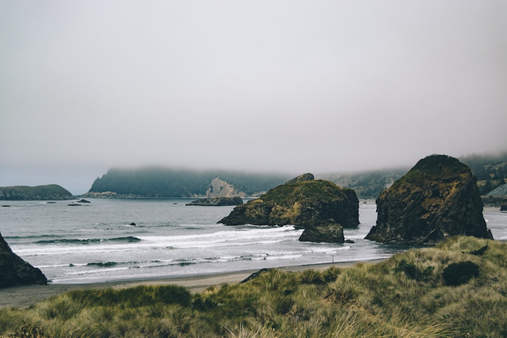 green and brown island on sea under gray sky