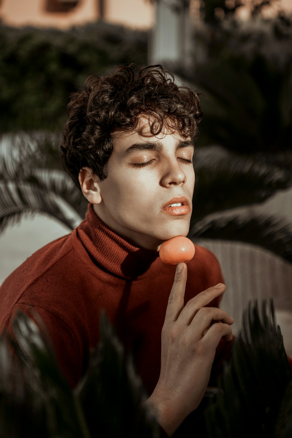 man in red sweater holding orange fruit