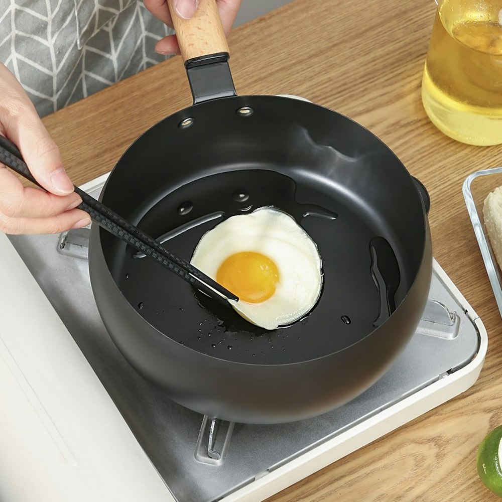 person cooking egg on black frying pan