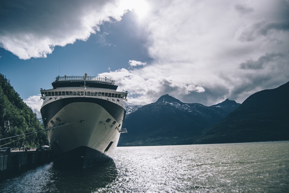 white ship on sea near mountain under white clouds during daytime